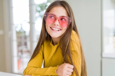 Pembe kalp gözlüğü takan güzel genç kız çocuk yan bakıyor ve düşünme uzağa bakıyor.