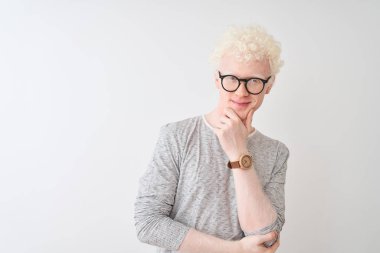 Genç albino sarışın adam çizgili t-shirt ve gözlük giyen izole beyaz arka plan üzerinde kamera güven görünümlü çapraz kollar ve el çene kaldırdı gülümseyerek. Olumlu düşünme.