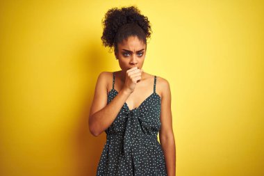 Izole sarı arka plan üzerinde yaz rahat yeşil elbise giyen Afro-Amerikan kadın rahatsız hissediyorum ve soğuk veya bronşit için bir belirti olarak öksürük. Sağlık kavramı.