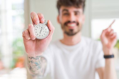 Tutan kronometreyi kullanan genç adam el ve parmakla yana doğru işaret etmekten çok mutlu