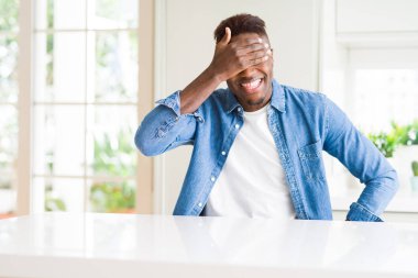Yakışıklı afro-amerikan adam evde gülümseyerek ve sürpriz için gözleri kaplayan yüzünde el ile gülüyor. Kör kavramı.