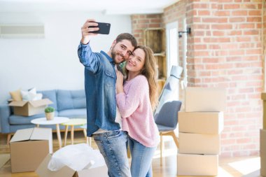 Yeni bir eve taşımak için çok mutlu gülümseyen Smartphone kullanarak bir selfie fotoğraf çekerken genç güzel çift