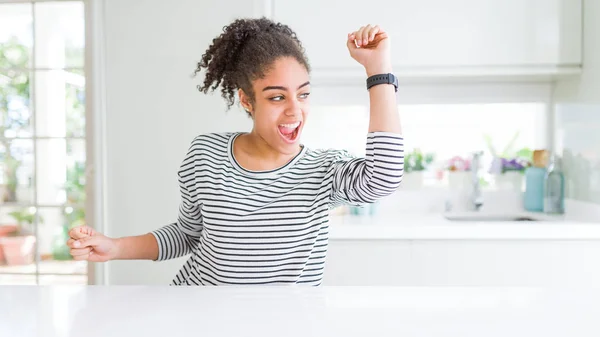 Beautiful african american woman with afro hair wearing casual striped sweater Dancing happy and cheerful, smiling moving casual and confident listening to music