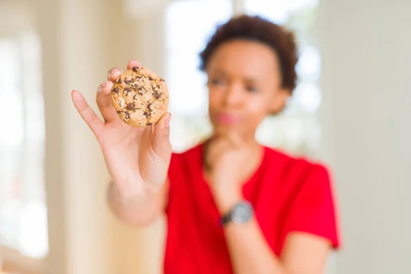 Junge Afrikanisch Amerikanische Frau Isst Schokoladenkekse Ernstes Gesicht Über Frage — Stockfoto