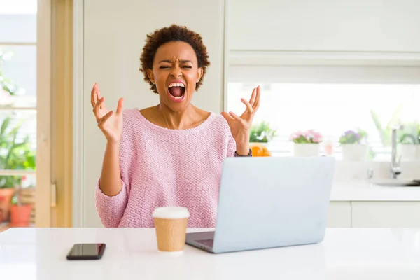 年轻的非洲裔美国妇女工作使用电脑笔记本电脑疯狂和疯狂的喊叫和大喊大叫 咄咄逼人的表情和手臂提出 挫折概念 — 图库照片
