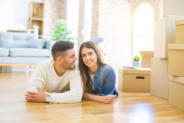 新しい家の床に横たわっている若い美しいカップルは 新しいアパートに引っ越すために非常に幸せに恋に微笑む — ストック写真