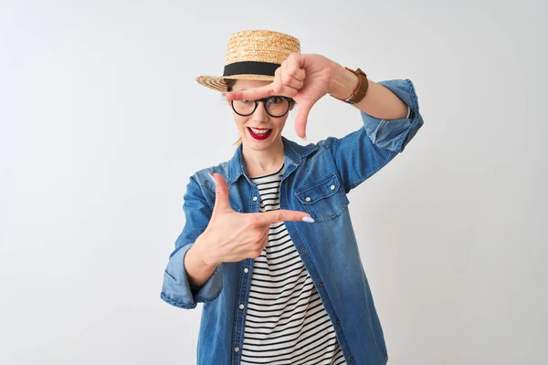 Redhead woman wearing denim shirt glasses and hat over isolated white background smiling making frame with hands and fingers with happy face. Creativity and photography concept.