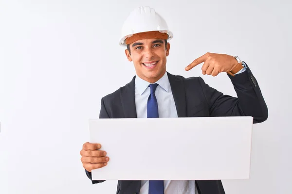年轻的英俊建筑师男子戴着头盔 在孤立的白色背景上举着横幅 惊喜的脸指向自己 — 图库照片