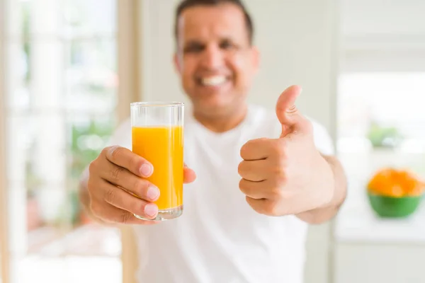 中年男子在家里喝一杯橙汁高兴 大笑着做好招牌 竖起大拇指 好招牌 — 图库照片