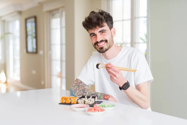 Young man eating sushi asian food using choopsticks