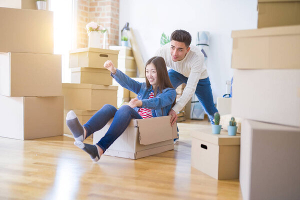 Funny asian couple having fun, riding inside cardboard box smili