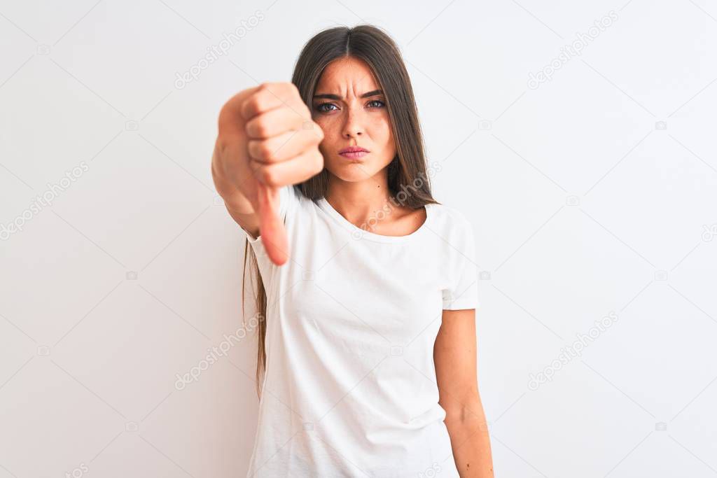 Young beautiful woman wearing casual t-shirt standing over isolated white background looking unhappy and angry showing rejection and negative with thumbs down gesture. Bad expression.
