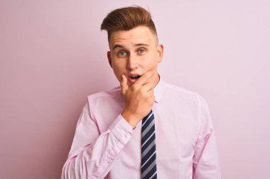 Genç yakışıklı işadamı gömlek ve kravat izole pembe arka plan üzerinde duran inançsızlık, sürpriz ve çene elleri ile hayran ifade hayran arıyorum