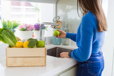 Genç kadın lavabo su kullanarak sebze ve meyve yıkama