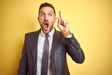 Başarılı bir fikir ile parmak işaret sarı izole arka plan üzerinde genç yakışıklı iş adamı. Çıktı ve mutlu. Bir numara.