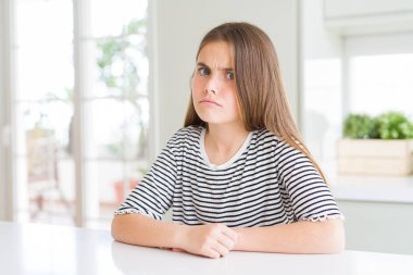 Beautiful young girl kid wearing stripes t-shirt skeptic and nervous, frowning upset because of problem. Negative person. clipart