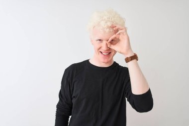 Genç albino sarışın adam siyah t-shirt giyen izole beyaz arka plan üzerinde duran el gülümseyerek ok jest yapıyor, mutlu yüz ile parmakları ile bakan göz.