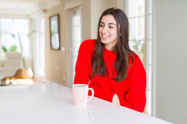 Güzel genç kadın, yüz, doğal ifade gülümseme ile kenara bakıyor siyah kahve bir fincan içme. Güven gülüyor.