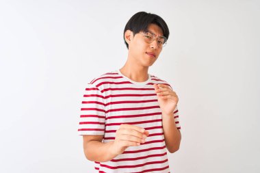 Gözlük takan ve çizgili tişört giyen genç adam izole beyaz arka plan üzerinde duran tiksinti ifade, hoşnutsuz ve korkulu tiksinti yüz yapıyor çünkü nefret tepki. Elleri havada. Sinir bozucu kavram.