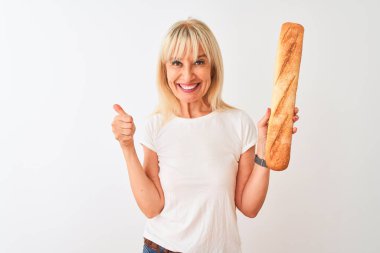 Orta yaş fırıncı kadın büyük bir gülümseme ok işareti yapıyor mutlu izole beyaz arka plan üzerinde duran ekmek tutan, parmakları ile başparmak, mükemmel işareti