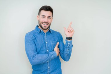 Kameraya bakarak yan el ve parmak ile işaret eden genç yakışıklı adam yüzünde kocaman bir gülümseme ile izole arka plan üzerinde.