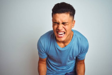 İzole beyaz arka plan üzerinde duran mavi t-shirt giyen genç Brezilyalı adam çok mutlu ve heyecanlı kolları kaldırdı ile kazanan jest yapıyor, gülümseyerek ve başarı için çığlık. Kutlama konsepti.