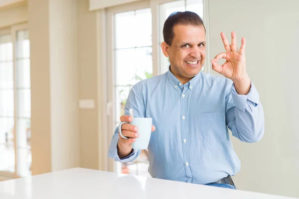 Hombre Mediana Edad Bebiendo Café Mañana Casa Haciendo Signo Con —  Fotos de Stock