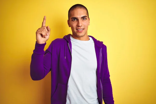 年轻的帅哥穿着紫色运动衫 在黄色孤立的背景上指着手指 成功的想法 退出和快乐 — 图库照片