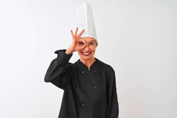 中年厨师妇女穿着制服和帽子站在孤立的白色背景做确定手势与手微笑 眼睛透过手指看快乐的脸 — 图库照片