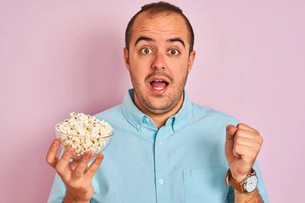 Jonge Man Holding Bowl Met Popcorn Staande Geïsoleerde Roze Achtergrond — Stockfoto