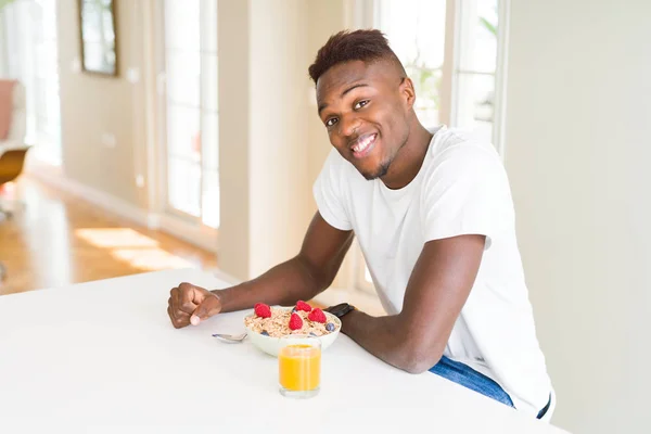 Handsome african american man eating heatlhy cereals and berries as breakfast