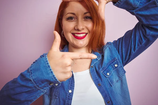 孤立したピンクの背景の上に立つ美しい赤毛の女性は 幸せな顔で手と指でフレームを作って笑顔 創造性と写真のコンセプト — ストック写真