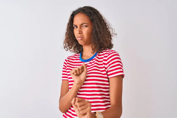 Young brazilian woman wearing red striped t-shirt standing over isolated white background disgusted expression, displeased and fearful doing disgust face because aversion reaction. With hands raised. Annoying concept.