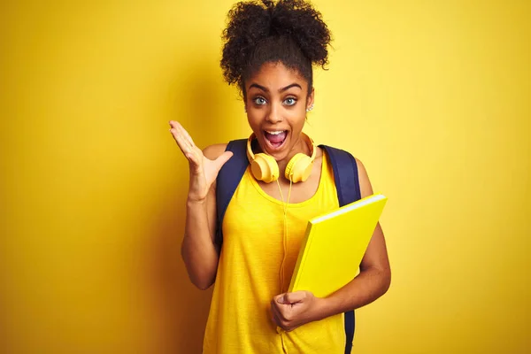 Afro Kvinna Med Ryggsäck Och Hörlurar Håller Anteckningsbok Över Isolerad — Stockfoto