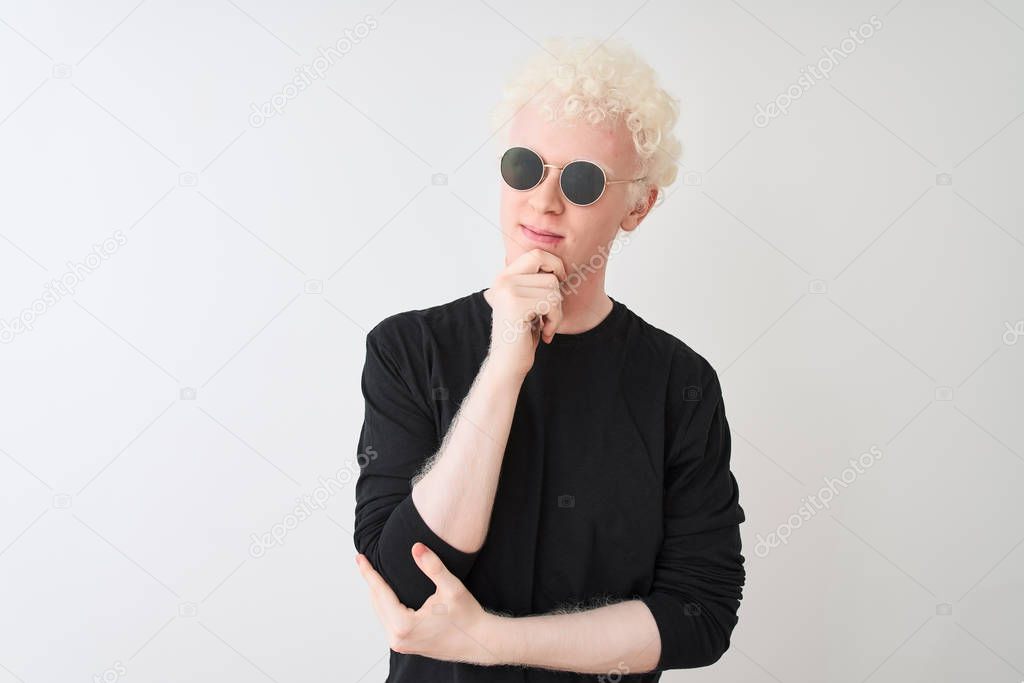 Young albino man wearing black t-shirt and sunglasess standing over isolated white background with hand on chin thinking about question, pensive expression. Smiling with thoughtful face. Doubt concept.