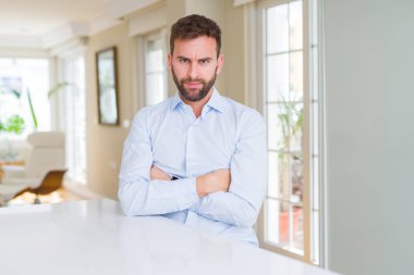 Yakışıklı iş adamı şüpheci ve sinirli, çapraz kolları ile yüzünde onaylamayan ifade. Negatif kişi.