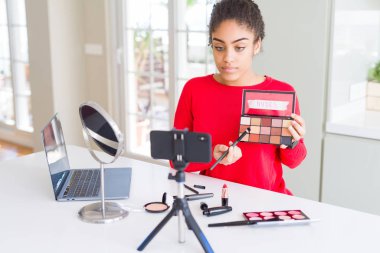 Genç afro-amerikan influencer kadın kayıt ciddi düşünme akıllı yüz kendine güvenen bir ifade ile öğretici makyaj