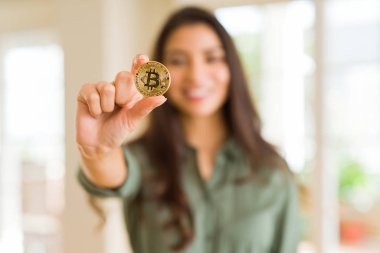 Bitcoin kriptoparalarını elektronik olarak tutarak gülümseyen genç kadın