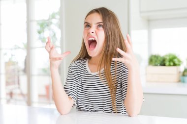Güzel genç kız çocuk çizgili t-shirt deli ve deli bağırarak giyen ve agresif ifade ve kollar kaldırdı ile bağırıyor. Hayal kırıklığı kavramı.