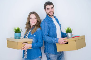 Beyaz izole arka plan üzerinde yeni bir eve taşımak için çok mutlu karton kutuları tutan genç güzel çift