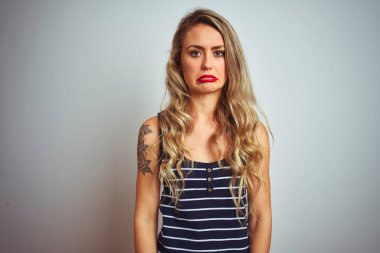 Çizgili t-shirt giyen genç güzel kadın beyaz izole arka plan depresif üzerinde duran ve sıkıntı için endişe, kızgın ve korkmuş ağlıyor. Hüzünlü ifade.