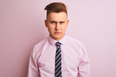 Genç yakışıklı işadamı gömlek giyen ve izole pembe arka plan üzerinde ayakta kravat depresif ve sıkıntı için endişe, kızgın ve korkmuş ağlıyor. Hüzünlü ifade.