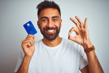 Genç hint müşteri adam parmaklar, mükemmel sembolü ile ok işareti yapıyor izole beyaz arka plan üzerinde duran kredi kartı tutan