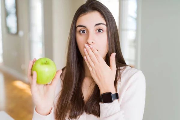 健康的な緑のリンゴのフルーツカバー口を食べる美しい若い女性は 間違いの恥ずかしさ 恐怖の表現 沈黙で怖がって 秘密の概念でショックを受けた手で口を覆います — ストック写真