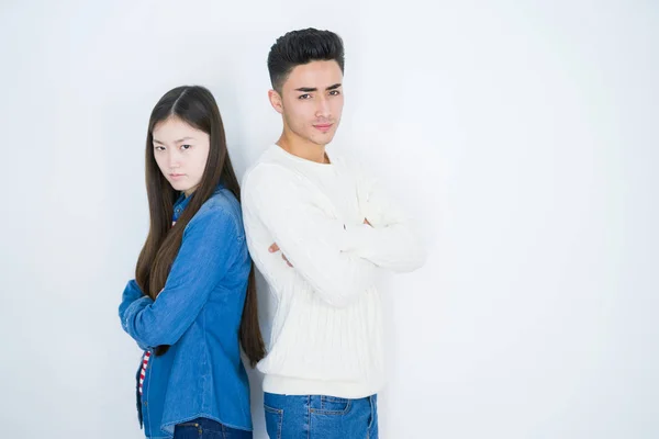 Beautiful young asian couple over white isolated background skeptic and nervous, disapproving expression on face with crossed arms. Negative person.