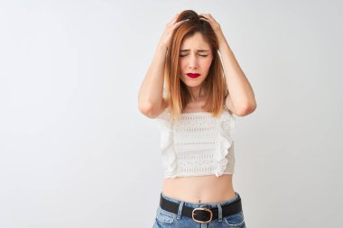 Güzel kızıl saçlı kadın rahat t-shirt izole beyaz arka plan üzerinde baş ağrısı umutsuz acı üzerinde duran giyen ve stresli çünkü ağrı ve migren. Eller baş üstünde.