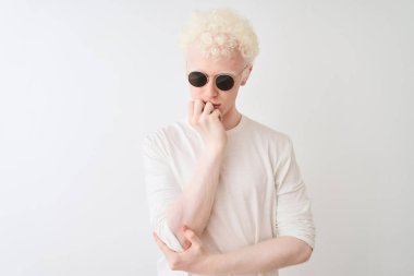Genç albino sarışın adam izole beyaz arka plan üzerinde t-shirt ve güneş gözlüğü giyen yorgun görünümlü ve çapraz kolları ile depresyon sorunları ile sıkılmış düşünme.