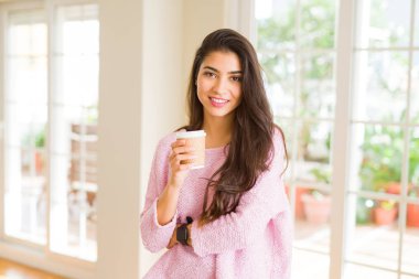 Güzel genç kız evde bir fincan kahve içme ve gülümseyerek