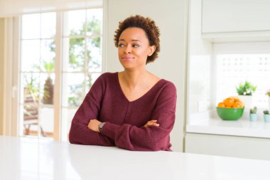 Genç güzel afro-amerikan kadın evde gülümseyen yan bakıyor ve düşünme uzak bakıyor.