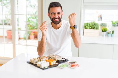 Chopsticks kullanarak Asya Suşi yeme yakışıklı İspanyol adam rahatsız ve öfke ile bağırarak sinirli, deli ve yükseltilmiş el, öfke kavramı ile bağırarak